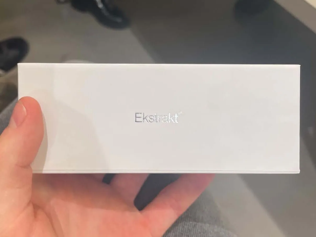 The white box held in a hand, with the Ekstrakt wordmark in silver