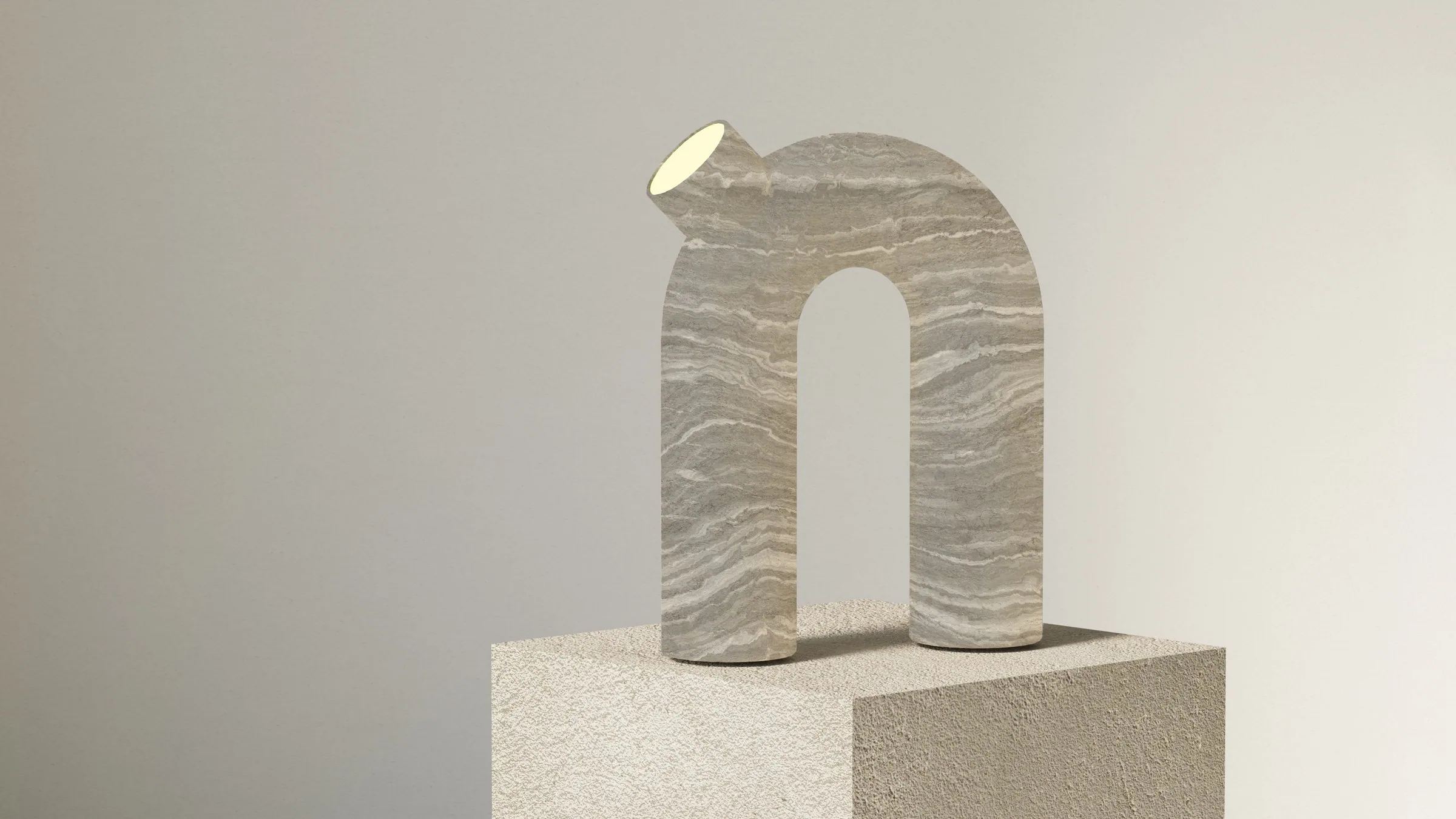 The arch lamp in sand-grey layered stone, seen at an angle